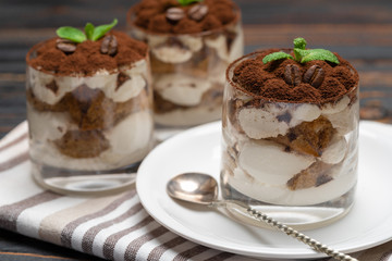 Classic tiramisu dessert in a glass on wooden background