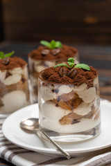 Classic tiramisu dessert in a glass on wooden background