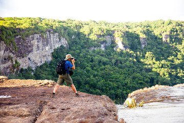 Tourists taking pictures of the river East Berbice front of the Kaieteur falls, Guyana. The...