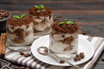 Classic tiramisu dessert in a glass on wooden background