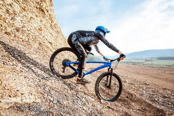 Professional well-equiped cyclist riding down on the rocky mountains. Concept of a freeride and off road cycling