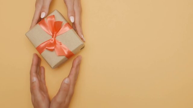 man giving a gift box woman top view, hands making present on special day on a colored cardboard background, the concept of holidays, love, romance