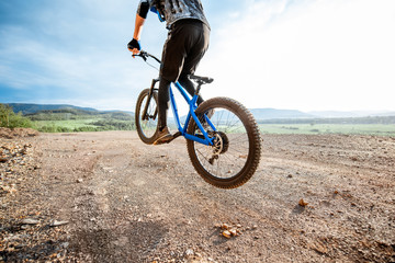 Professional well-equipped cyclist riding bicycle on the rocky mountains with beautiful landscape view during the sunset