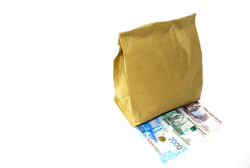 Money lying next to a paper bag on a white background
