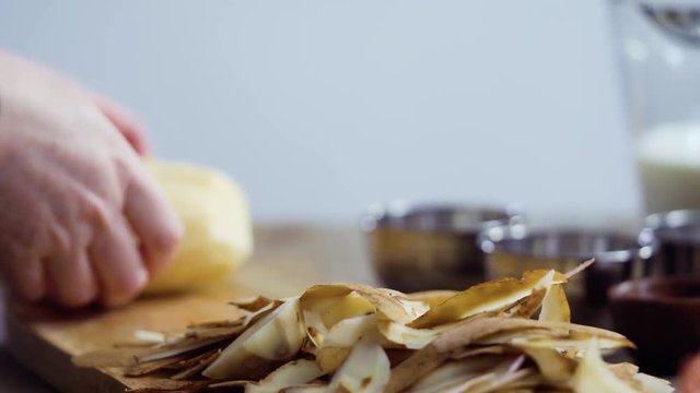 Time lapse. Slicing organic gold potatoes on a V-blade mandoline to prepare scalloped potatoes.