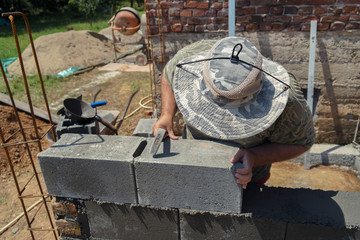 Industrial worker, bricklayer or mason laying bricks and creating walls.