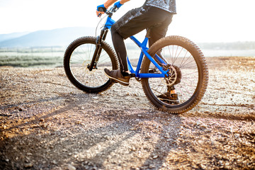 Fototapeta premium Man riding bicycle on the rocky mountains, cropped image with no face