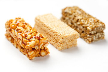 Grain granola bar with peanuts, sesame and seeds in a row on a white background. Top view Three assorted bars, isolate