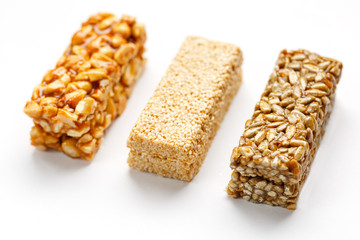 Grain granola bar with peanuts, sesame and seeds in a row on a white background. Top view Three assorted bars, isolate