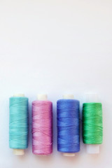 Multicolored thread coils on pink blue background. Sewing supplies and accessories for needlework, stitching, embroidery. space for text. flat lay, top view 