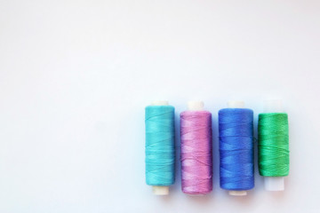 Multicolored thread coils on pink blue background. Sewing supplies and accessories for needlework, stitching, embroidery. space for text. flat lay, top view 
