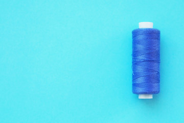 Multicolored thread coils on pink blue background. Sewing supplies and accessories for needlework, stitching, embroidery. space for text. flat lay, top view 
