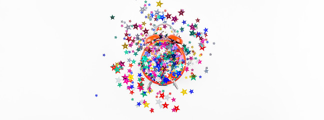 Festive star confetti with red alarm clock concept
