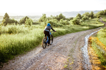 Fototapeta premium Professional well-equipped cyclist riding down on the mountain road during the sunset