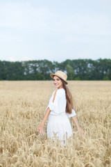 Fototapeta na wymiar Beautiful summer girl a wheat field, a white dress, A sunny day. Teenage model summer holidays, vacation and people concept. Rich harvest Concept. Beauty girl portrait in wheat field at sunset.