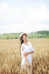 Fototapeta na wymiar Beauty girl portrait in wheat field at sunset. Attractive young woman smiling and enjoying life. Beautiful brunette with a healthy long haircut. Wellness concept. Rich harvest Concept. 