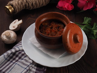 Mushroom stew with vegetables and raw mushrooms on the background