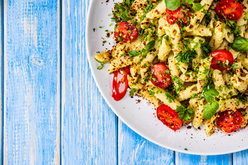 Pasta with herbs and vegetables on wooden background