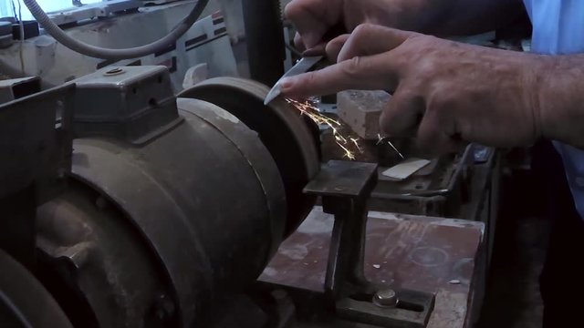 Man sharpens a knife on an emery machine