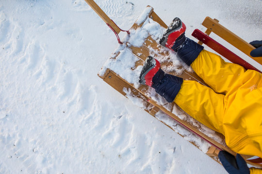 High angle of toddler sitting in wooden sled during winter.