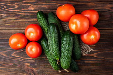 Fresh cucumbers and tomatoes on dark wooden background..