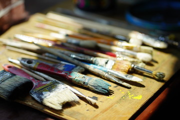 Obraz premium Artist brushes lie on a wooden board. The working environment of the artist for the background.