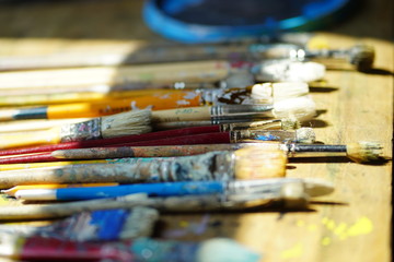 Fototapeta premium Artist brushes lie on a wooden board. The working environment of the artist for the background.
