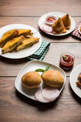 Indian Tea time snacks  in group includes Veg Samosa, Kachori/kachaudi, aloo bonda, khaman dhokla, bread, onion,chilli and moong pakora/pakoda/bhaji/bhajji/Bhajiya/bajji with sauces, selective focus