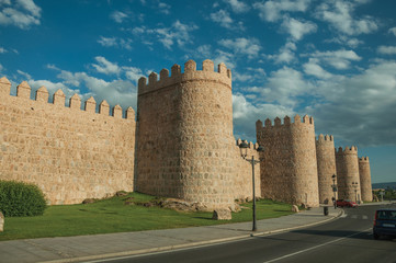 Fototapeta na wymiar Street and light posts beside towers in the wall around Avila