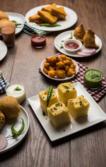 Indian Tea time snacks  in group includes Veg Samosa, Kachori/kachaudi, aloo bonda, khaman dhokla, bread, onion,chilli and moong pakora/pakoda/bhaji/bhajji/Bhajiya/bajji with sauces, selective focus