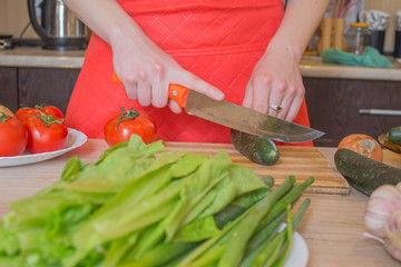 woman cooking healthy meal in the kitchen. Cooking healthy food at home. Woman in kitchen preparing vegetables. Chef cuts the vegetables into a meal