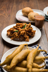 Indian Tea time snacks  in group includes Veg Samosa, Kachori/kachaudi, aloo bonda, khaman dhokla, bread, onion,chilli and moong pakora/pakoda/bhaji/bhajji/Bhajiya/bajji with sauces, selective focus