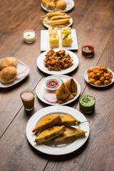 Indian Tea time snacks  in group includes Veg Samosa, Kachori/kachaudi, aloo bonda, khaman dhokla, bread, onion,chilli and moong pakora/pakoda/bhaji/bhajji/Bhajiya/bajji with sauces, selective focus