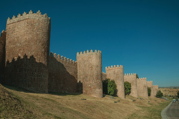 Stone towers on the large city wall next to street at Avila