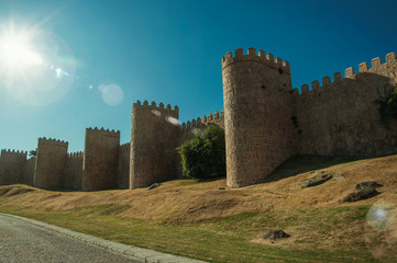 Sunbeam above the large city wall and green lawn at Avila