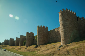 Sunbeam above the large city wall and green lawn at Avila