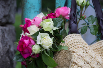 bouquet of fragrant English pink and white roses in a bag of raffia hanging on the fence