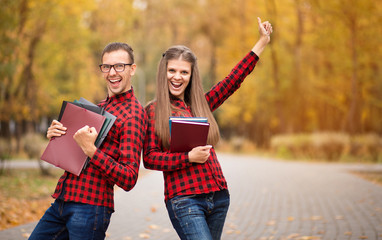 Two excited students with hands up and approved exams in autumn
