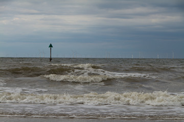 Marker buoy on coast with large windfarm on horizon
