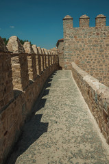 Fototapeta na wymiar Pathway over thick stone wall with battlement around Avila