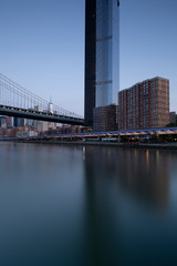 Fototapeta na wymiar Financial District with One Manhattan Square building view from East River with long exposure during sunrise