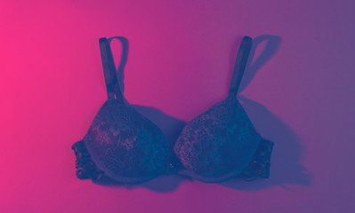 Erotic concept. Women's sexy bra, neon pink light. Top view