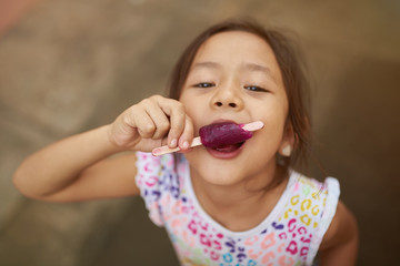 Small girl bites ice cream