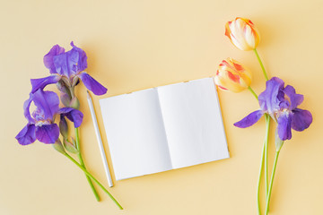 Mockup white notebook with yellow tulips and blue irises on a yellow background