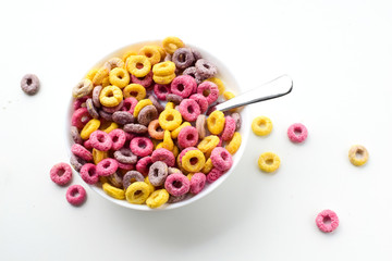 Multicolored round-shaped flakes lie in a bowl on a light background. Delicious and healthy breakfast for children.