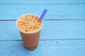 Pearl Bubble milk tea with ice in plastic cup on wooden floors