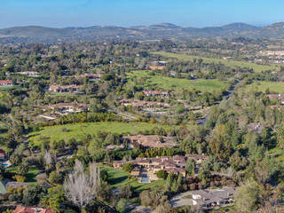Fototapeta na wymiar Aerial view of wealthy countryside area with luxury villas with swimming pool, surrounded by forest and mountain valley. Ranch Santa Fe. San Diego, California, USA.