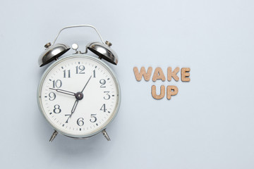 Retro alarm clock on gray background with text wake up with letters. Top view. Minimalistic concept