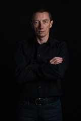 outdoor portrait of a very beautiful serious man, dark hair, posing in classic suit on black background