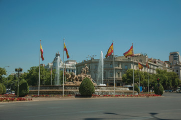 Street and Cybele fountain with Spanish flags in Madrid